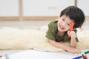 Montessori Families - A small boy coloring on the floor