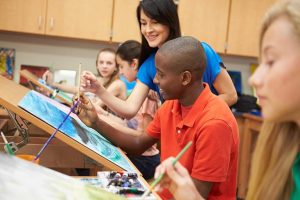 Schools and Program Leaders - Boy in orange shirt painting